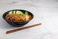 Closeup of a bowl of Vietnamese grilled pork on noodles and chopsticks on a white table