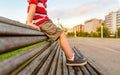 Boy legs sitting on the top of bench park relaxing