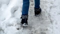 Closeup of boy in snowboots walking over covered snowdrifts and road covered with snow and ice Royalty Free Stock Photo