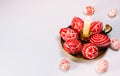 Closeup brass candlestick with Easter red eggs with folk white pattern stand on white background and eggs scattered around. Ukrain