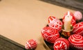 Closeup brass candlestick with Easter red eggs with folk white pattern stand on paper on rustic table background. Ukrainian tradit