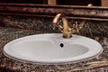 Closeup of a brass faucet with hot and cold handles on a white lavatory sink in a restroom