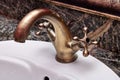 Closeup of a brass faucet with hot and cold handles on a white lavatory sink in a restroom Royalty Free Stock Photo