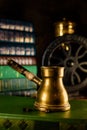 Closeup brass turk with beans beside and coffee grinder on background. Atmosphere of old library with old books around on dark