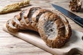 Closeup bread loaf and wheat ears and knife on wooden background