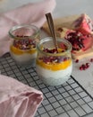 Closeup of breakfast jars with coconut grater and mango puree mix, chia seeds and pomegranate