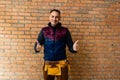 Closeup of bricklayer hands holding hardhat and construction equipment. Handyman with tools belt Royalty Free Stock Photo
