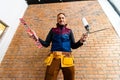 Closeup of bricklayer hands holding hardhat and construction equipment. Handyman with tools belt