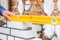 A closeup of a bricklayer worker installing wite blocks and caulking brick masonry joints exterior wall with trowel putty knife ou Royalty Free Stock Photo