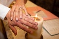 Closeup of bride and groom after exchanging wedding rings with church candle