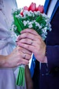 Closeup of the bride's and groom's hands holding a wedding bouquet, a vertical shot Royalty Free Stock Photo