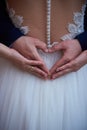 Closeup of bride& x27;s and groom& x27;s hands forming heart shape on wedding gown Royalty Free Stock Photo