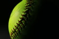 Closeup of a bright, yellow softball with red seams. Royalty Free Stock Photo