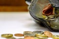 Closeup of British currency coins open from the piggy bank laid out scattered on white table and wooden background