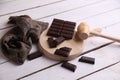 Closeup of a broken chocolate bar on a wooden board a wooden mallet and a patterned cloth