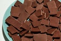Closeup of broken, crushed dark chocolate bars stack on a plate isolated over white background