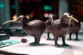 Closeup of bronze kiwi bird statues on the table under the lights with a blurry background