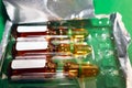 Closeup of Brown Empty Opened Glass Ampoule with White Labels, Its Head, and Full Ampoules with Liquid Medicine in a Plastic Royalty Free Stock Photo