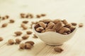 Closeup of brown fresh almonds seed in white bowl on wooden table