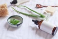 Closeup of a brown glass bottle around aloe leaves on a white cloth