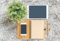 Closeup brown note book , brown pen , computer notebook , tablet , phone and artificial plant on gray fabric capet textured backgr Royalty Free Stock Photo