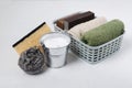 Closeup of bucket full of baking soda, metal scrubber, basket with towel, natural soap and sponges on the white table.Concept of e