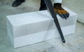 Closeup builder sawing aerated concrete block with hand saw