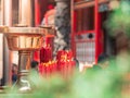 Closeup bundle of big red candles burning near the golden tray at Longshan temple.