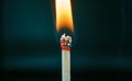 Closeup of burning match with red sulfur head on dark background Royalty Free Stock Photo