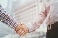 Closeup of a business man with luggage travel hand shake between two colleagues greet