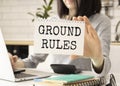 Business woman holding a card with text GROUND RULES, business concept image with soft focus background and vintage