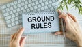 Closeup on businessman holding a card with text GROUND RULES, business concept image with soft focus background.