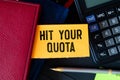 Closeup on businessman holding a card with text HIT YOUR QUOTA, business concept