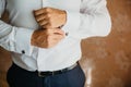 Closeup businessman puts on cufflinks, wears expensive leather belt. Man in a business suit, white shirt. Preparing the Royalty Free Stock Photo