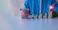 Closeup of businessman putting coins on heap of coins at table, saving money concept