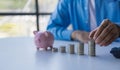 Closeup of businessman putting coins on heap of coins at table, saving money concept Royalty Free Stock Photo