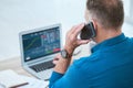 Closeup of a businessman using a phone and laptop, trading on the stock market in a financial crisis. Online trader with Royalty Free Stock Photo
