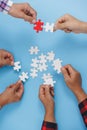 Closeup of businesspeople holding jigsaw puzzle on a blue background. Hand holding the puzzles for the businessmen to work Royalty Free Stock Photo