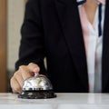 Closeup of a businesswoman hand ringing silver service bell on hotel reception desk