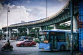 Closeup of a busy highway in Bangkok with a bridge and cloudy sky in the background