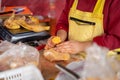 Closeup of a butcher cutting up a chicken on a wooden cutting board in the market