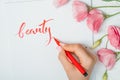 Closeup of calligrapher hands writes word beauty on white paper. Inscribing ornamental decorated letters. Calligraphy