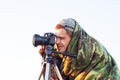 Closeup of a camouflaged paparazzi photographer taking picture Royalty Free Stock Photo