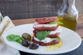 Closeup Caprese Salad with sliced red tomato, buffalo mozzarella, basil leaves and healthy whole olives dripping in extra virgin o Royalty Free Stock Photo