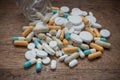 Capsules and drug tablets falling from bottle on wood