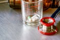 Closeup capsules and tablet in a glass with Medical stethoscope on aluminum plate