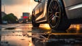 closeup of car wheel with light alloy aluminium disc and tire in wet water puddle after rain, wet asphalt at autumn day Royalty Free Stock Photo