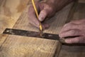 Closeup of carpenter marking line on wood board with pencil and wooden square Royalty Free Stock Photo