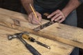 Closeup of carpenter marking line on wooded board with pencil and wooden square during home remodel