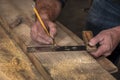 Closeup carpenter marking measurement on wood board with old wooden handle square and pencil Royalty Free Stock Photo